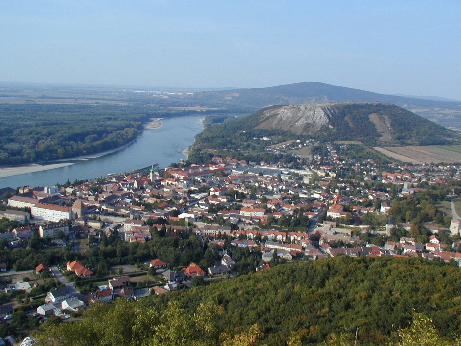 Panoramic view of a city with a river and hills in the background.