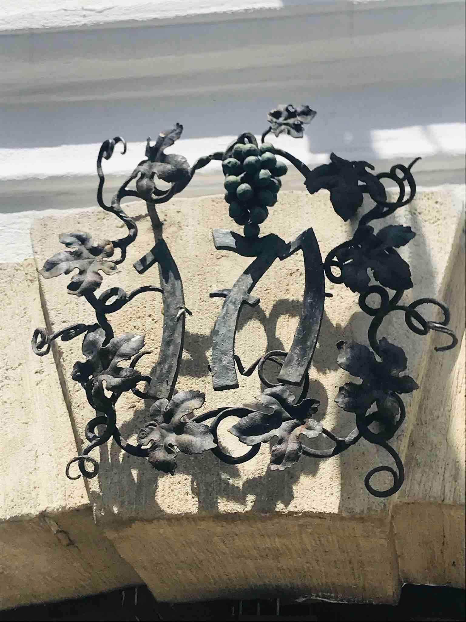 Metal decoration with grape motif and the number 1717 on a stone arch.