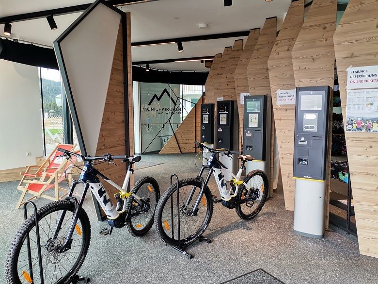 Interior view of an e-MTB rental shop with bikes and ticket machines.