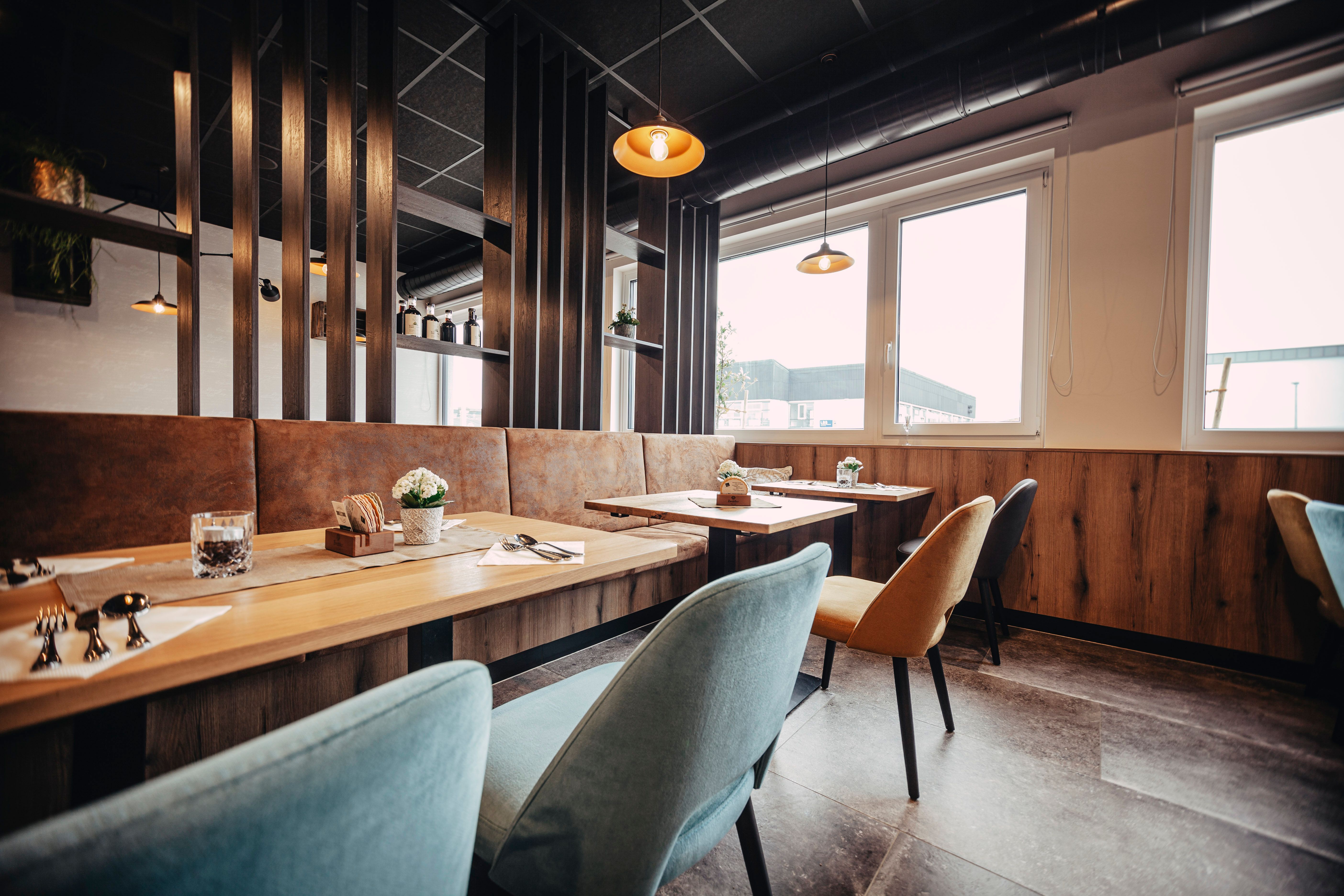 Modern restaurant with wooden tables, colorful chairs and large windows.