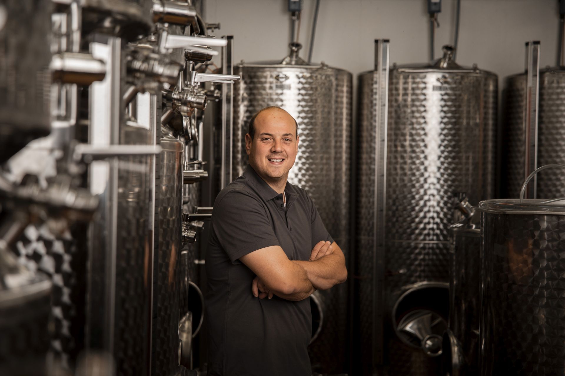 Man in a wine cellar with stainless steel barrels.
