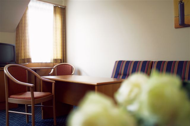 Hotel room with table, chairs and sofa.
