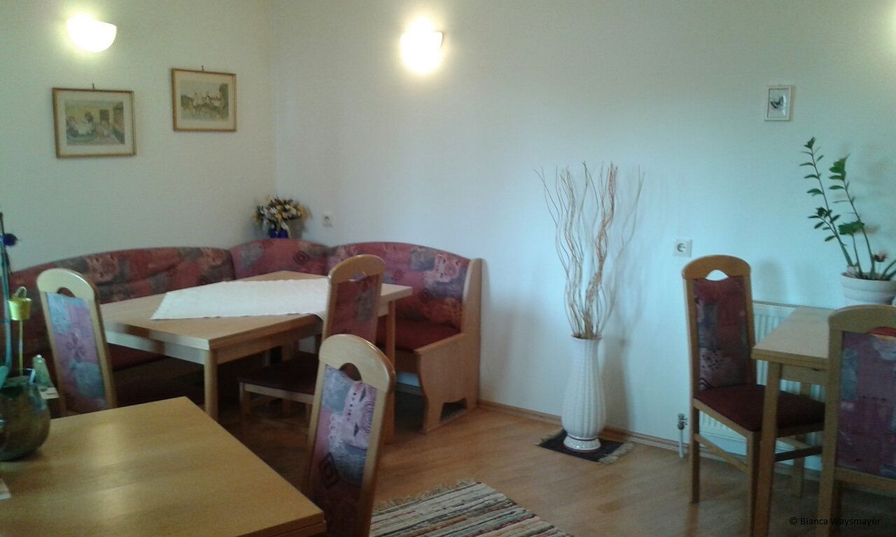 Cozy seating area in a communal kitchen with wooden tables and upholstered chairs.