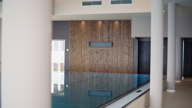 Interior view of an infinity pool at the Hotel Schachner with wooden cladding and modern columns.