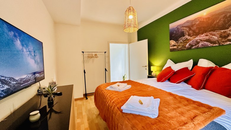 Cozy bedroom with green accent, double bed, TV and decoration.