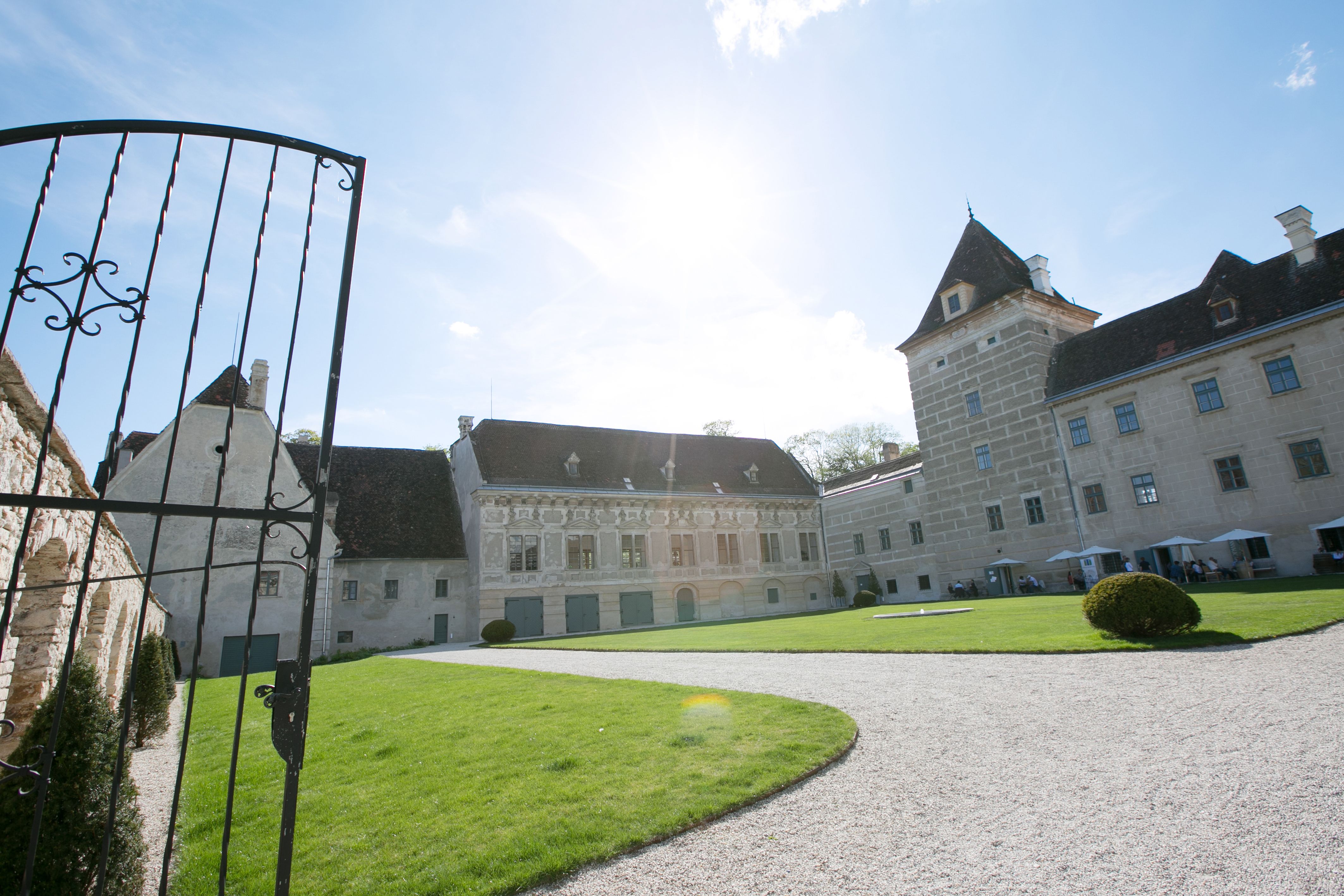 Entrance to Walpersdorf Castle with open gate, lawn and historic building in the background.