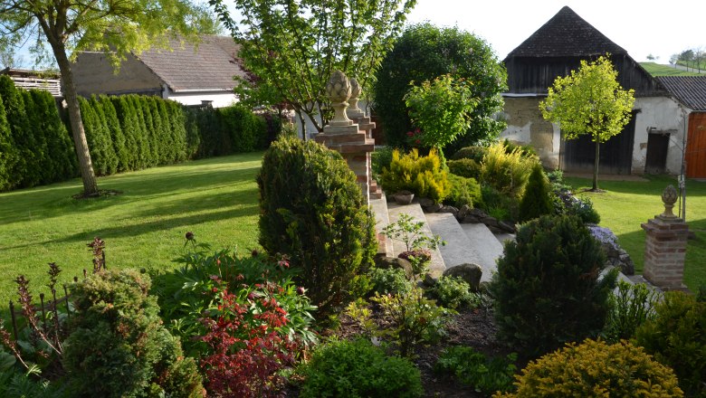 A well-kept garden with lawn, bushes and trees, surrounded by buildings in the background.