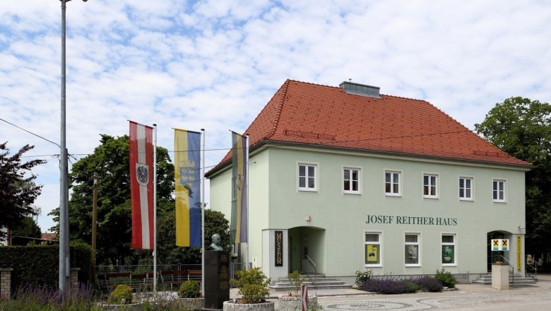 Josef Reither house with flags and bust in the foreground.