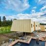 Modern wooden garden lofts with steps, surrounded by nature and a pond in the foreground.