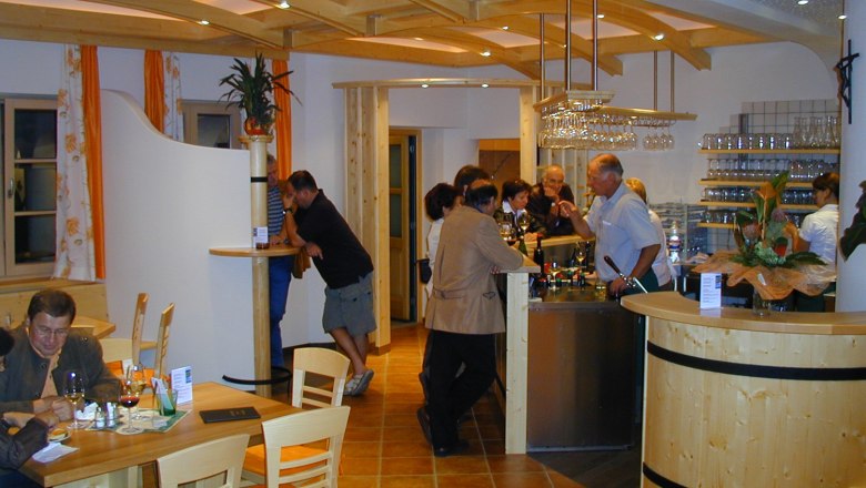 Interior view of a wine tavern with guests at the bar and at tables.