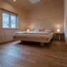 Wood-paneled bedroom with double bed and bedside lamps.