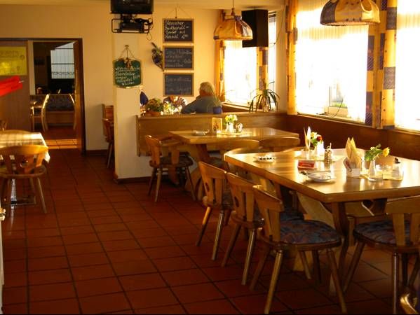 Cozy dining room with wooden tables and chairs, decorated with flowers and napkins.