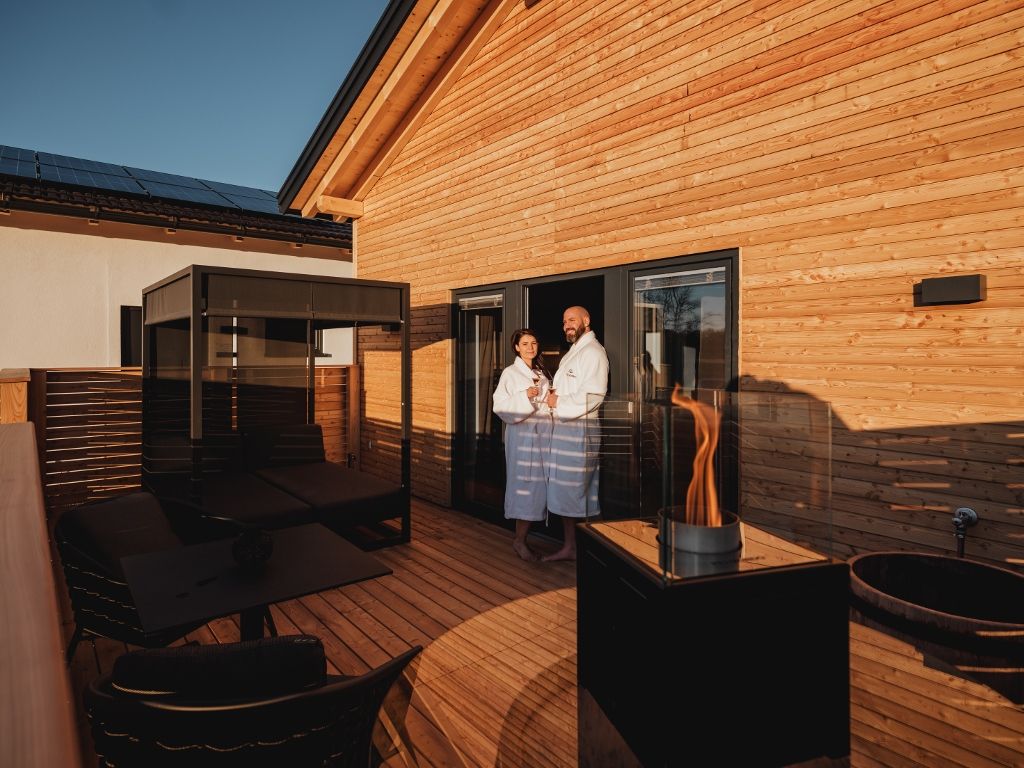 Terrace with four-poster bed, fireplace and two people in bathrobes.