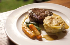 A plate with a piece of meat, vegetables and a potato side dish.
