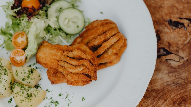 A plate of breaded fish, potatoes and salad.