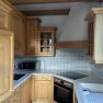 Kitchen with wooden units, stove, sink and microwave.