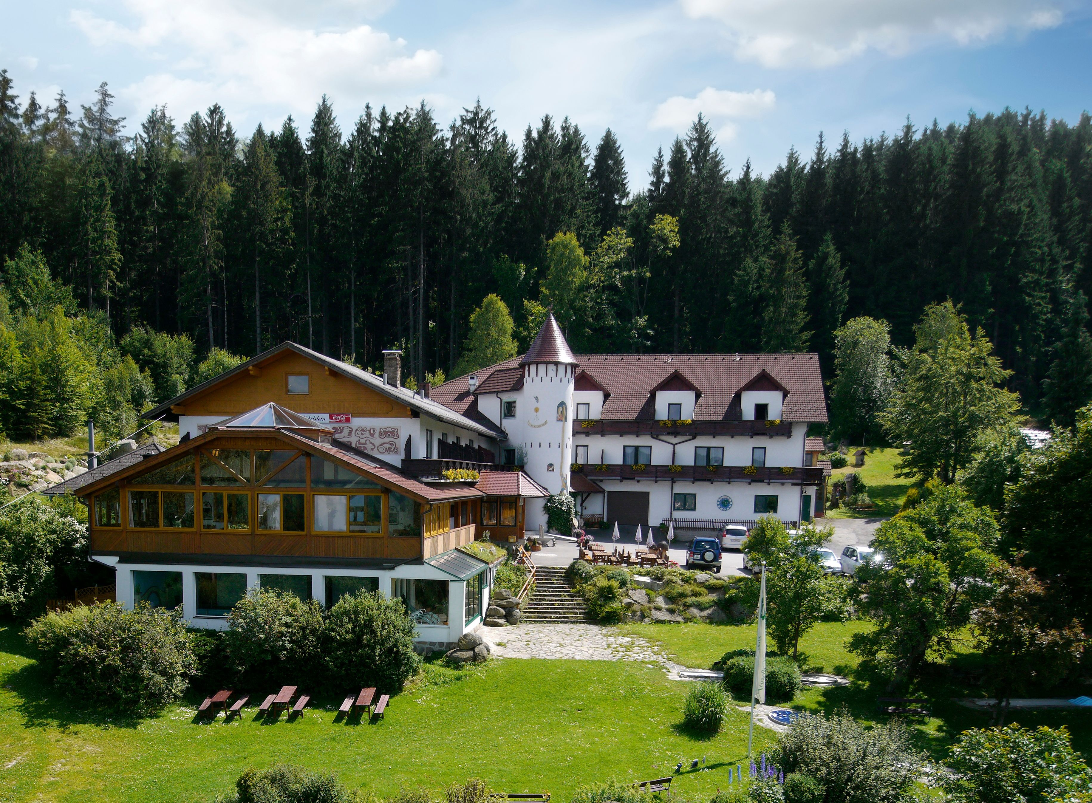 A hotel in the forest with a tower and garden.