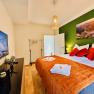 Cozy bedroom with green accent, double bed, TV and decoration.