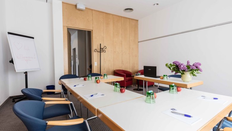 Conference room with tables, chairs, flipchart and flowers.