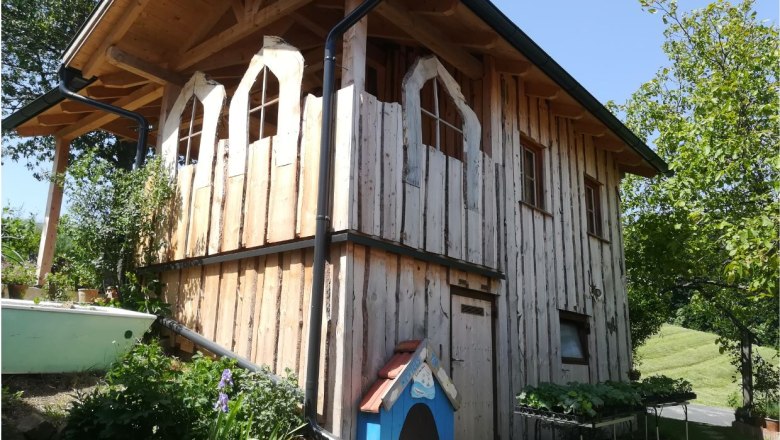 Wooden house in a natural garden with plants.