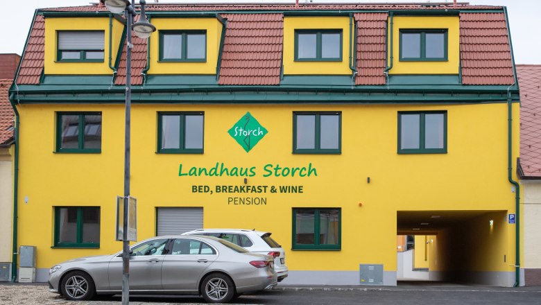 Country house Storch, © Nadine Beles Yellow building with the inscription 'Landhaus Storch', cars parked in front of it.