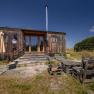 Wooden house with terrace and pallet furniture in a rural setting.