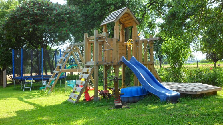 A playground in the garden with climbing frame, slide and trampoline.