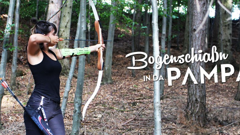 A woman shoots with a bow in the forest. The text "Bogenschia&szlig;n in da Pampa" is superimposed.