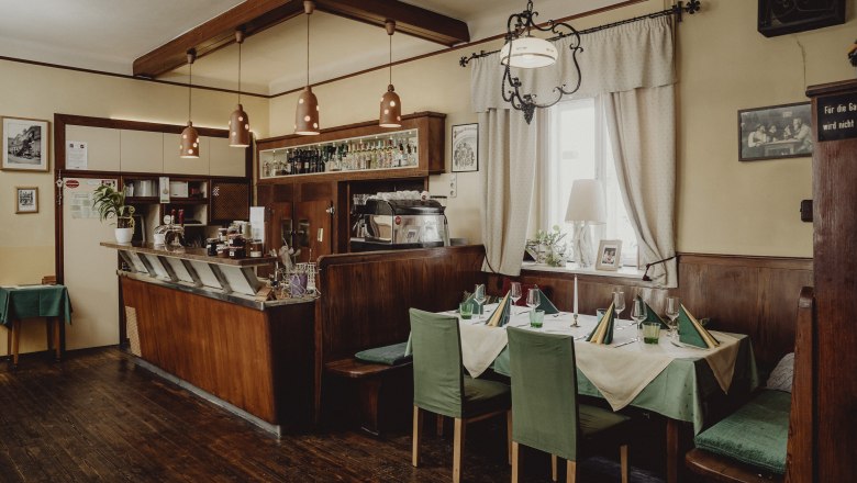 Cozy café with wooden furniture, set table and bar area.