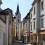 Narrow alley with old buildings and church tower in the background.