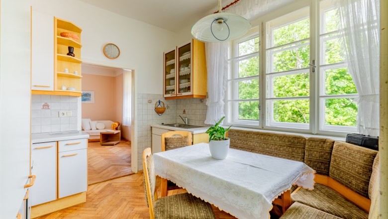 Bright kitchen with dining area, table, chairs and window with a view of the greenery.