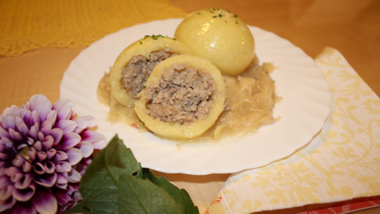 A plate of Waldviertel meat dumplings on sauerkraut, decorated with a flower.