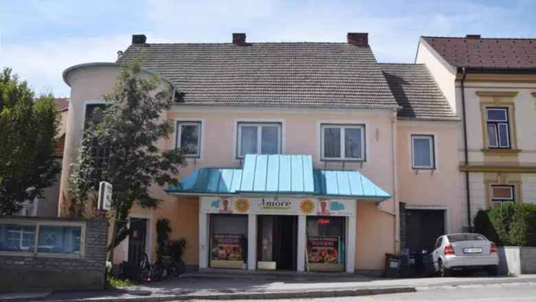 A small restaurant with a blue awning and a car in front of it.