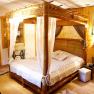 Cozy bedroom with wooden four-poster bed and rustic furnishings.