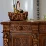 A carved wooden buffet with a basket and cups on it.