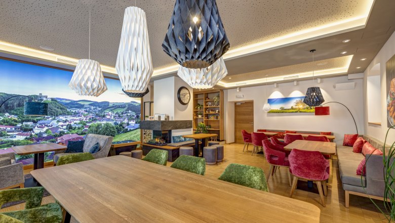 Interior view of a modern bistro with wooden tables, colorful chairs and large, decorative lamps.