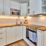 Modern kitchen with white cupboards, wooden worktops, stove and sink.