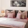 Cozy bedroom with double bed, pink bed linen and two bedside tables with lamps.