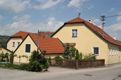 Yellow house with red roof in a rural setting.