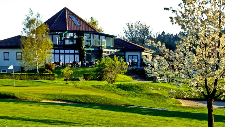Clubhouse of the Ottenstein Golf Club with a blossoming tree in the foreground.