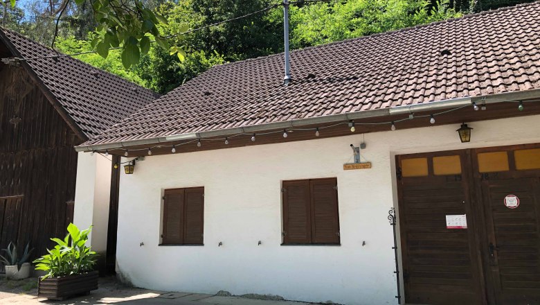Exterior view of a wine tavern with a white fa&ccedil;ade and wooden door.