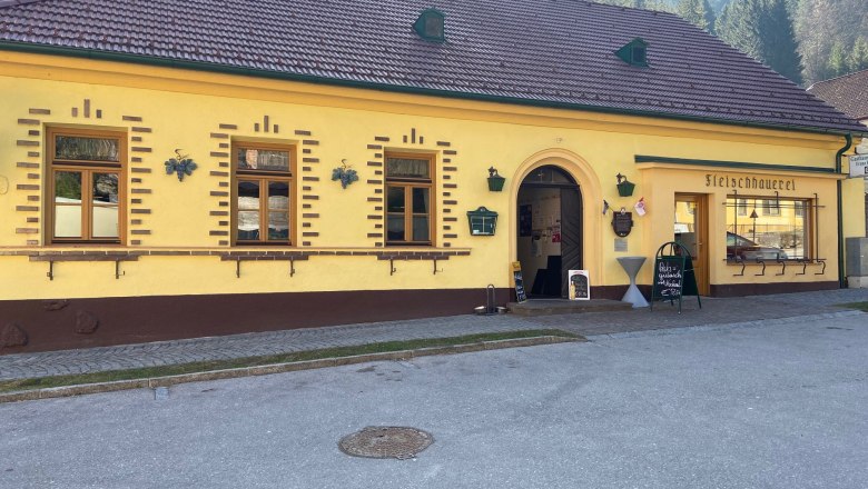 Yellow building with the inscription 'Fleischhauerei' and an entrance.