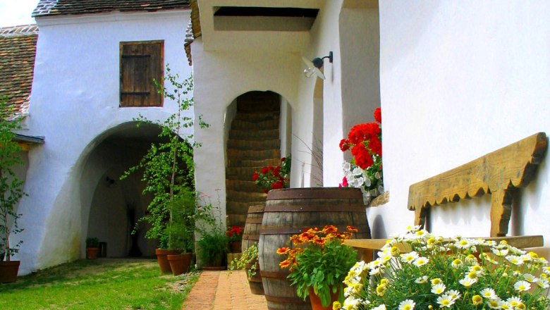 Traditional courtyard with flowers and wooden barrels.