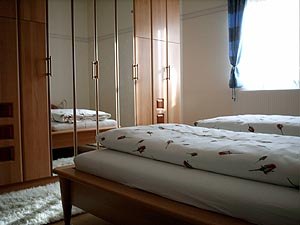 One bedroom with wooden furniture, a double bed and a large closet with mirrors.