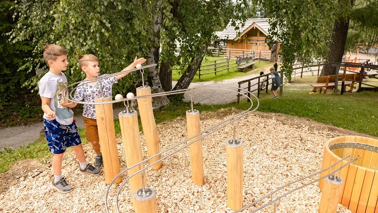 Two children playing on an outdoor marble run.