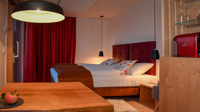 Cozy hotel room with double bed, red curtains and wooden furniture.