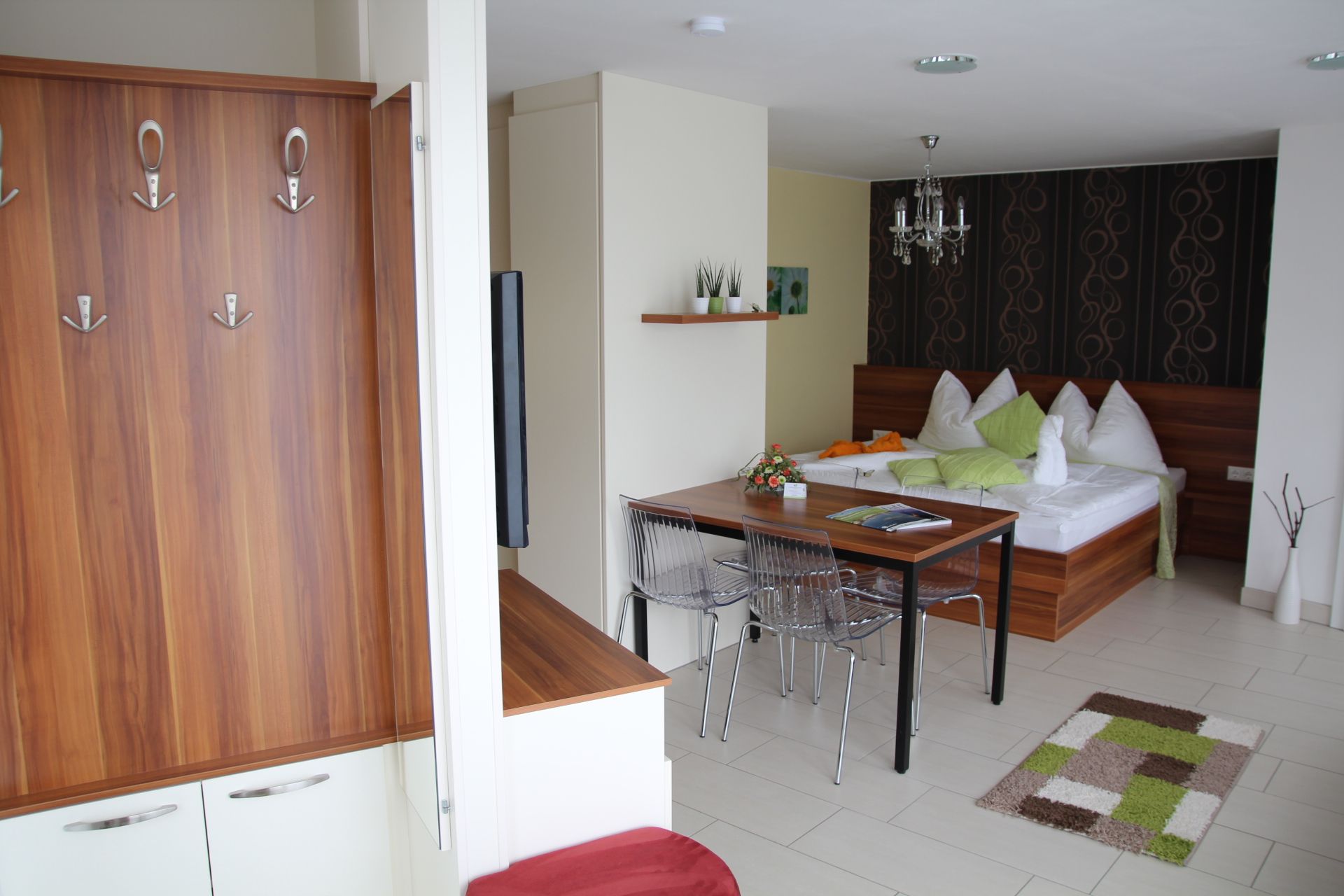 Modern apartment with wooden furniture, dining table, bed and decorative elements.