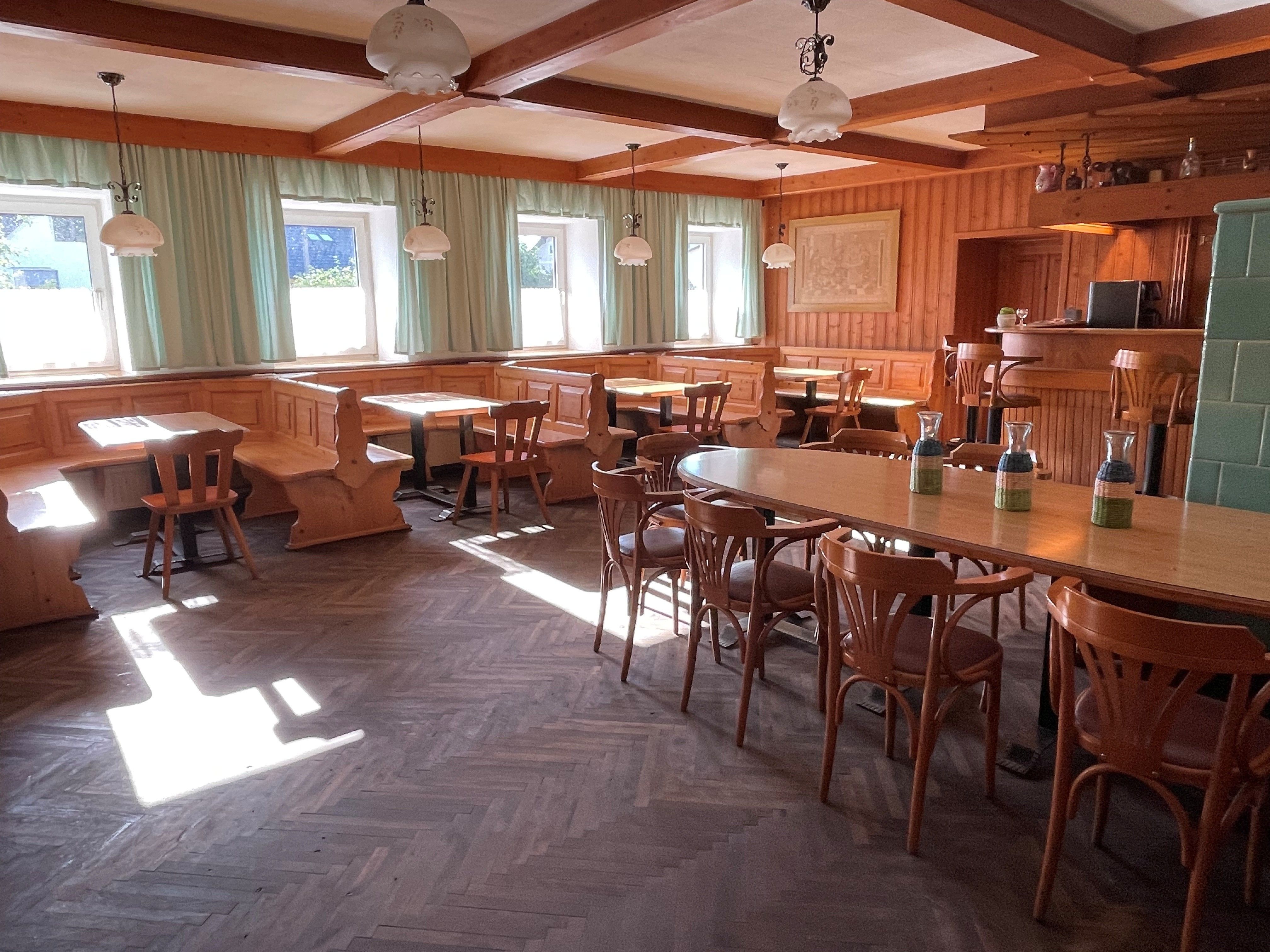 A cozy dining room with wooden furniture and large windows that let in plenty of light.