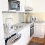 Modern kitchen with white cupboards, sink, dishwasher, microwave and coffee machine.