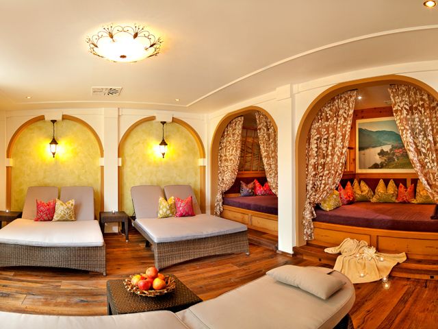 A cozy wellness room with loungers, curtains and cushions.